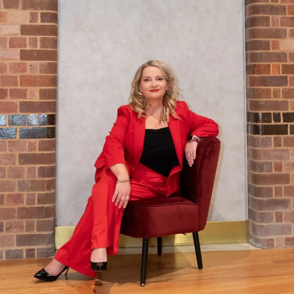 Juanita Wheeler seated in a red suit at the Thomas Dixon Centre in Brisbane.