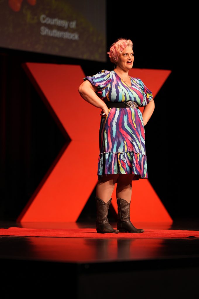 Jenny Wynter standing in the red circle, in front of the giant red X on the TEDxBrisbane stage.